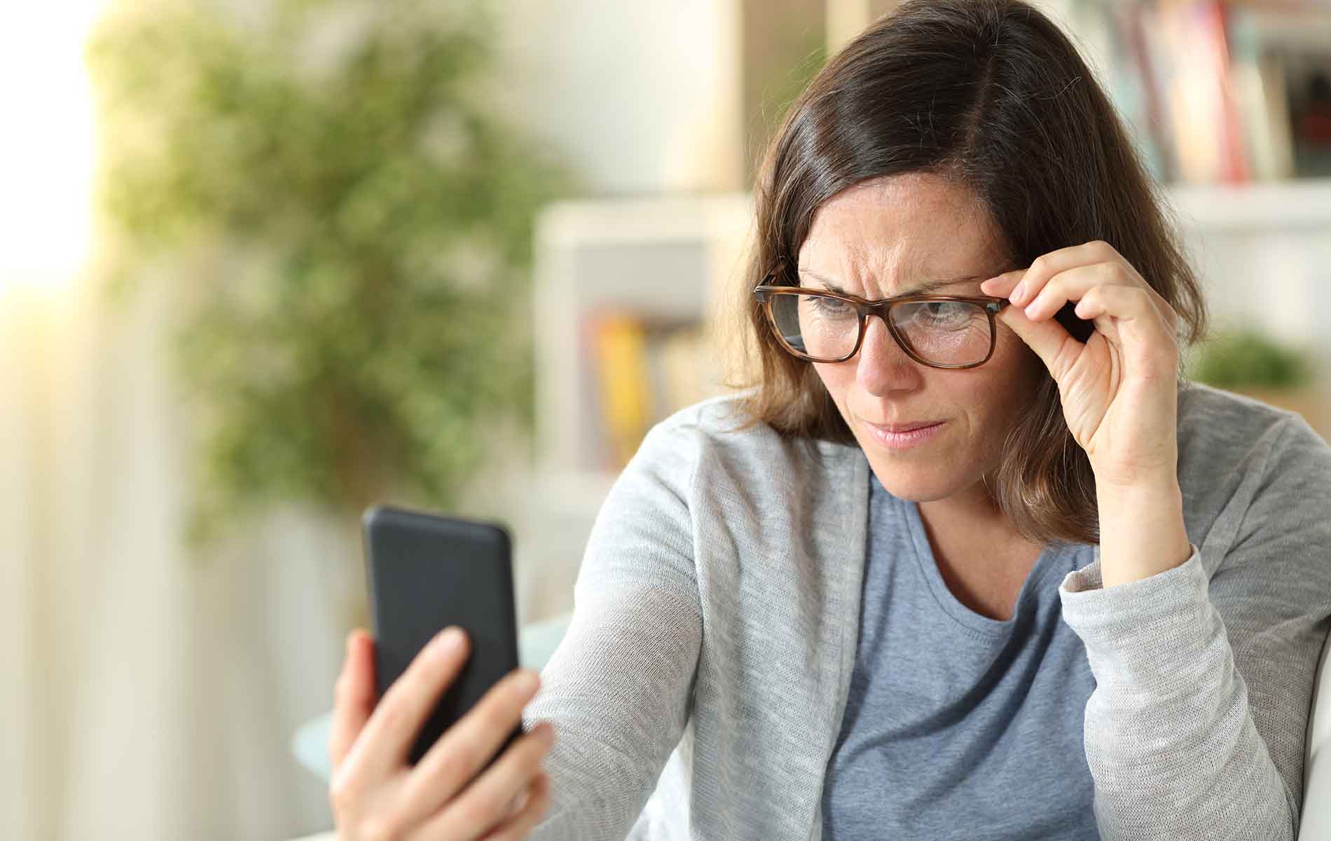 Woman having problem seeing  her mobile phone screen through the glasses.