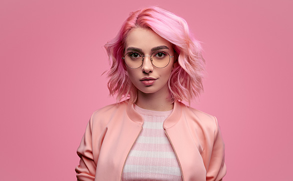 Young girl  wearing glasses with pink hair on a pink background