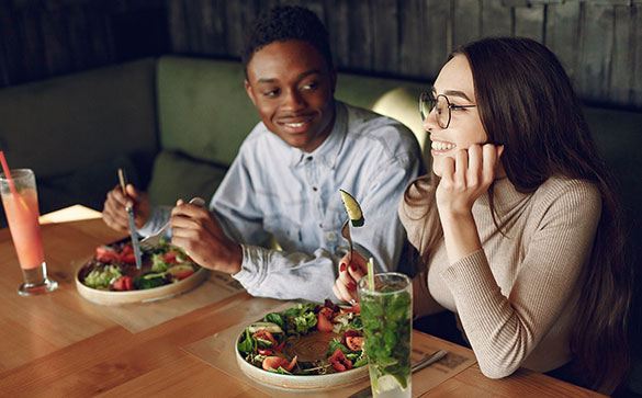 Couple of young people eating meal in a restaurant